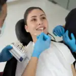Dentist matching veneer shade to female patient's teeth during cosmetic consultation